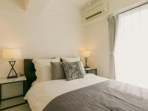 a bedroom with a bed and two lamps and a window at Aiwa Mansion / Vacation STAY 80384 in Naha