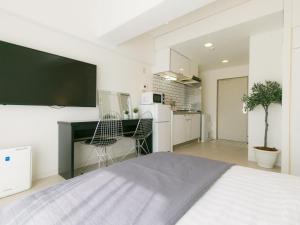 a bedroom with a bed and a desk and a kitchen at Aiwa Mansion / Vacation STAY 80384 in Naha