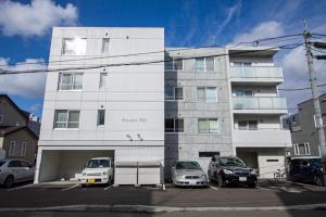 a white building with cars parked in a parking lot at Premiere N21 / Vacation STAY 7452 in Sapporo