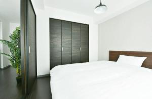 Suncourt Hondori Garden Hills / Vacation STAY 7592 في سابورو: غرفة نوم بسرير أبيض و اللوح الأمامي أسود