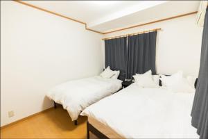 two beds in a room with black curtains at Fukuoka - House / Vacation STAY 81254 in Fukuoka
