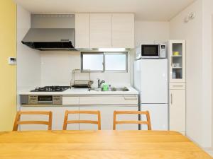 a kitchen with a white refrigerator and a table and chairs at Kinugawa Station Front room B in Nikko