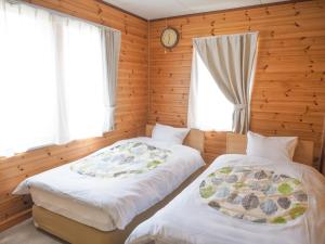 two beds in a room with wooden walls and windows at Nasu-gun - House - Vacation STAY 7648 in Nasu