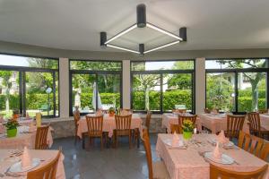 a dining room with tables and chairs and windows at Hotel Montecarlo in Lido di Camaiore