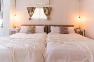 2 camas en un dormitorio con sábanas y almohadas blancas en Bijou Suites Sorriso - Vacation STAY 7862, en Osaka