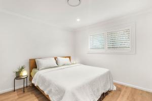 a white bedroom with a bed and a window at Moon Tide in Lennox Head +6 photos