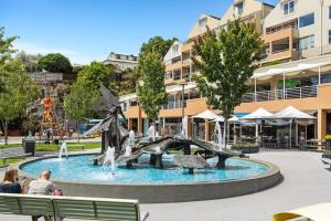 a fountain in a park with people sitting on a bench at Kelly Street Cottage in Historic Battery Point in Hobart