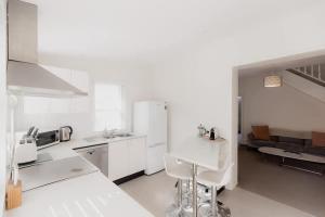 a white kitchen with white appliances and a couch at Kelly Street Cottage in Historic Battery Point in Hobart