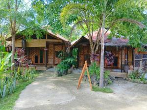 a wooden house with a sign in front of it at Herbs Guest House and Restaurant near the Sea in Moalboal