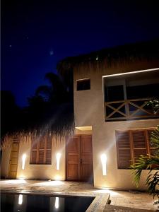 a house with a building with a straw roof at night at LA VICTORIA Casa tropical con piscina privada in Carmen de Apicalá +15 photos