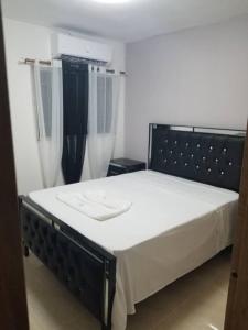 a bedroom with a bed with a black headboard and curtains at Comfy Palace in San Isidro