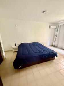 een bed in een kamer met een blauwe deken op de vloer bij Apartamento frente a Bahía de Pampatar in Pampatar