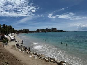 een strand met mensen die in het water zwemmen bij Apartamento frente a Bahía de Pampatar in Pampatar