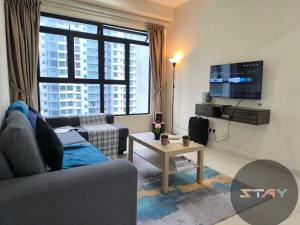 スクダイにあるThe Garden 3BR Family Cozy Suites Netflix BySTAYのソファ、テレビ、テーブルのあるリビングルーム