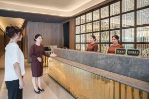 Un gruppo di donne in piedi al bar di 上海浦东机场祝桥桔子水晶酒店 a Shanghai