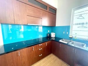 une cuisine avec des armoires en bois, un évier et une fenêtre dans l'établissement Blue Sea Hon Chong - Beachfront Apartment, à Nha Trang 57 autres photos