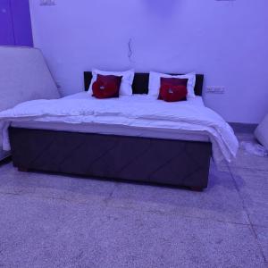 ジョードプルにあるHotel the saffron leaf innの赤い枕2つが付いたベッド1台