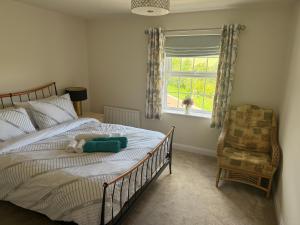 a bedroom with a bed and a window and a chair at Comfortable 5-Guests Abode - In Quiet Village in Lincolnshire
