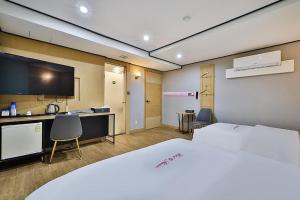 a room with a bed and a desk and a tv at Motel Flower in Seoul