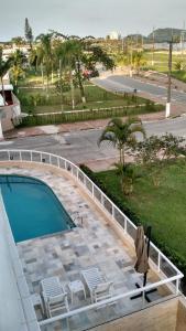 a balcony with a swimming pool and chairs at Indaia Apartamento de Frente ao Mar in Bertioga