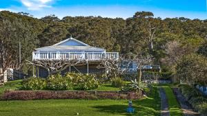a house with a white deck and a yard at 'Torcello - Waterfront on the Bay' by HolidayCo in Hardys Bay