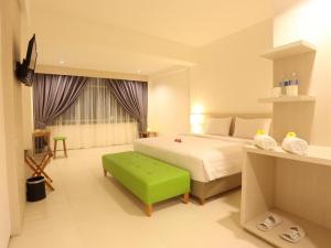 a bedroom with a bed and a green ottoman at Fovere Hotel Palangkaraya in Palangkaraya +65 photos