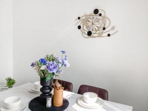 ein Tisch mit einer Blumenvase und einer Uhr in der Unterkunft Amayrah Cottage in Inverness