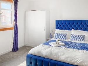 ein blaues Bett mit blauem Kopfteil in einem Schlafzimmer in der Unterkunft Amayrah Cottage in Inverness
