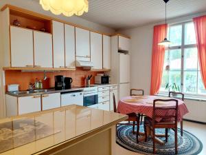 a kitchen with white cabinets and a table with chairs at Taideniityn huoneisto Taika 1 - 6lle in Varkaus