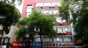 a tall red building with a tree in front of it at Shell Ganzhou Central Theme Hotel in Ganzhou