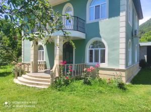 a blue house with stairs and flowers in the yard at Gabala Garden & Mountain View Villa in Gabala