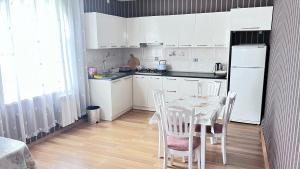 a kitchen with white cabinets and a table with chairs at Gabala Garden & Mountain View Villa in Gabala