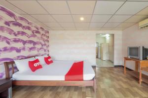 a bedroom with a bed with red pillows and a tv at OYO 1152 Hongpak Mint in Ban Bang Saen (1)