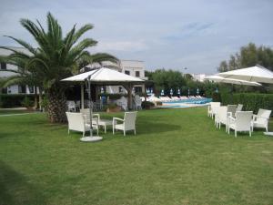 a row of white chairs and umbrellas on a lawn at Residence Club Barbara in Ostuni