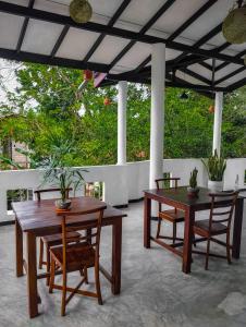 two wooden tables and chairs on a patio at Mirissa Villa Green Pepper in Mirissa