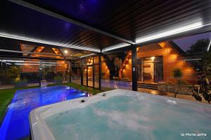 a hot tub in the backyard of a house at Campanga nera - ארבע בקתות מדהימות עם בריכה מחוממת וג'קוזי in Yarka