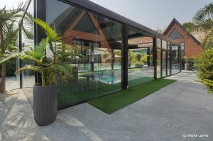 a large glass house with a potted plant on a patio at Campanga nera - ארבע בקתות מדהימות עם בריכה מחוממת וג'קוזי in Yarka