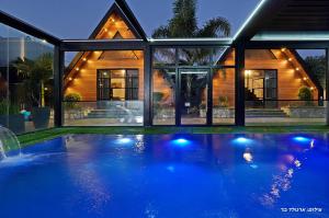 a house with a swimming pool in front of a house at Campanga nera - ארבע בקתות מדהימות עם בריכה מחוממת וג'קוזי in Yarka