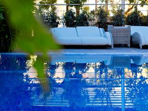 a white couch sitting next to a pool of water at The Cookbook Gastro Boutique Hotel & SPA in Calpe