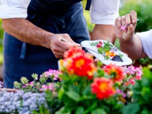 a person holding a plate with flowers on it at The Cookbook Gastro Boutique Hotel & SPA in Calpe
