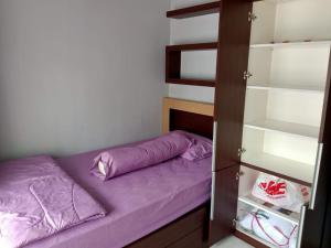 a small bed with purple sheets in a bedroom at Stylish House Near Pakuwon Mall in Kejayan