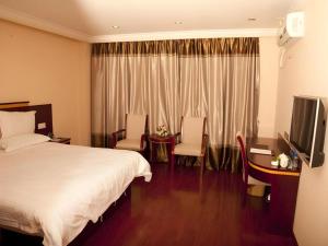 a hotel room with a bed and a desk and a television at GreenTree Inn Shanghai Minhang Development Zone Subway Station Business Hotel in Shanghai