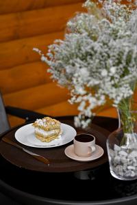 a plate of cake and a cup of coffee and a vase with flowers at Abraham's Greenland in Artavaz