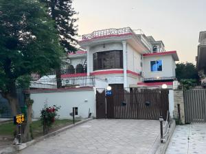una casa blanca con una puerta y una valla en Decent Luxury Guest House F-10, en Islamabad