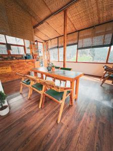 un tavolo in legno e una panca in una stanza con finestre di Young Monk Hostel & Cafe Jibhi a Jibhi