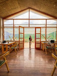 una persona in piedi in una grande stanza con tavoli di Young Monk Hostel & Cafe Jibhi a Jibhi Altre 15 foto