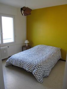 a bedroom with a bed with a yellow wall at Appartement Le Cap in Toulon