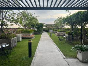 ein Gehweg in einem Garten mit Tischen und Stühlen in der Unterkunft Cozy9Living in Bangkok 60mto MRT in Ban Bang Khwang