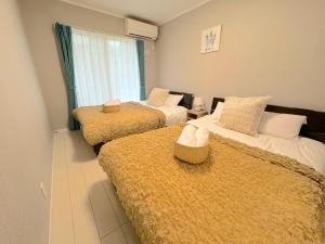Zimmer mit 3 Betten und gelben Decken in der Unterkunft Grande Ortho Okinawa Villa Onna 3 - Vacation STAY 91374 in Meta