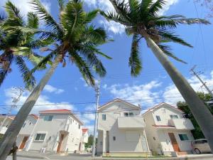two palm trees in front of a row of houses at Grande Ortho Okinawa Villa Onna 3 - Vacation STAY 91370 in Onna